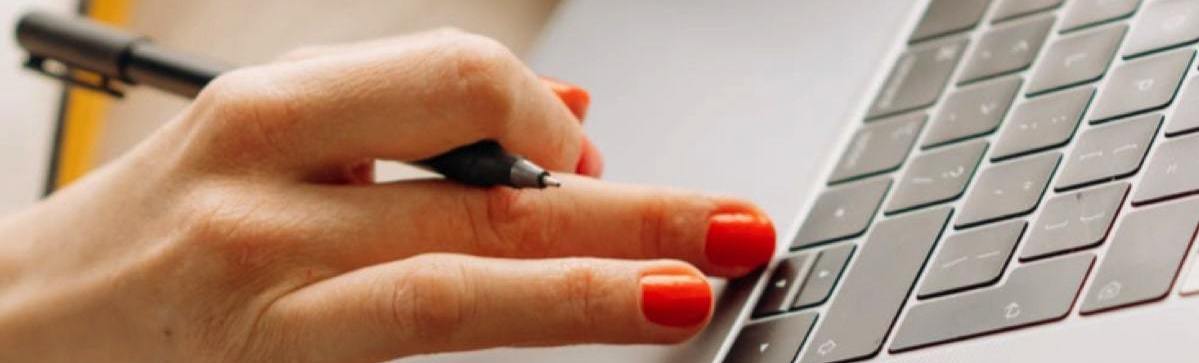 Hand holding pen using keyboard representing company secretary services